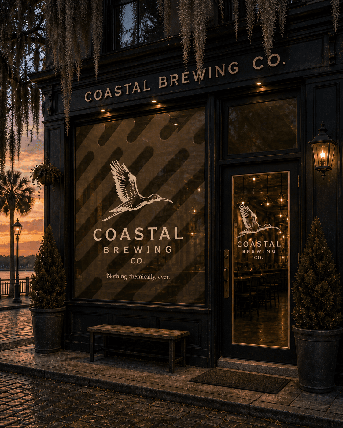 Coastal Brewing Co. storefront at sunset — wood-stork logo and 'Nothing chemically, ever.' on the window, Spanish moss hanging from a live oak, palm tree and oil lamp at the curb, brick walkway.